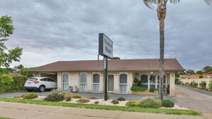 Un motel con un letrero, un coche estacionado al frente y un césped bien cuidado.