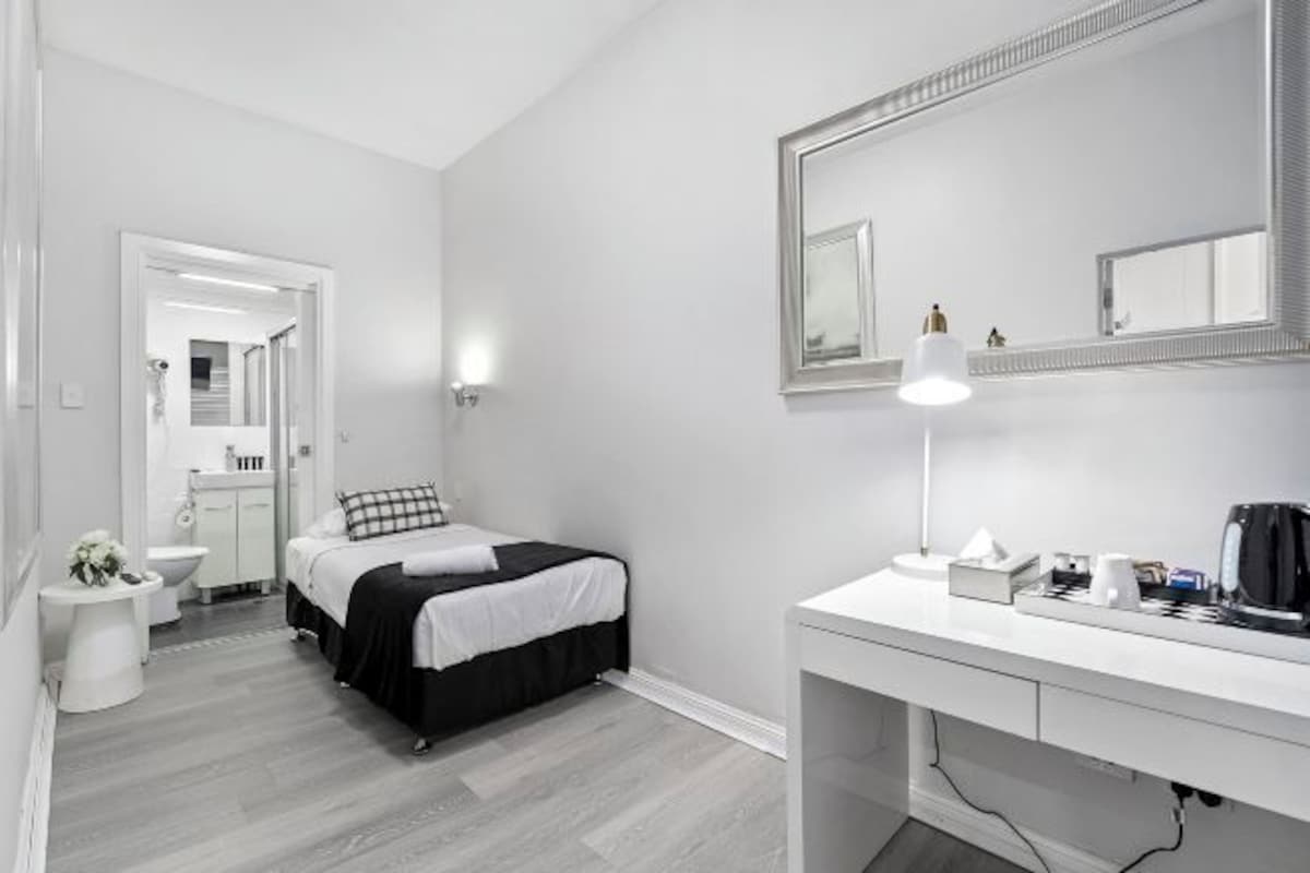A modern bedroom with a bed, bedside table, and a large mirror.