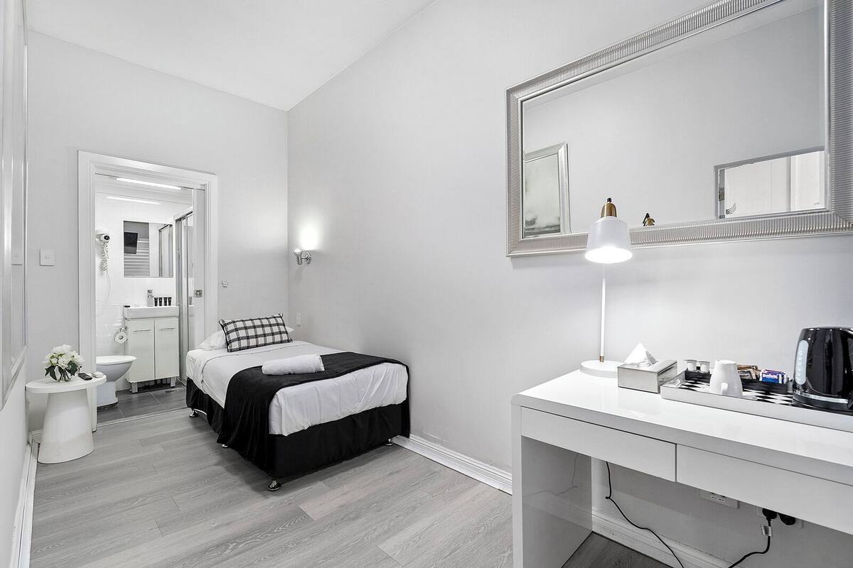 A modern bedroom with a bed, bedside table, and a large mirror.