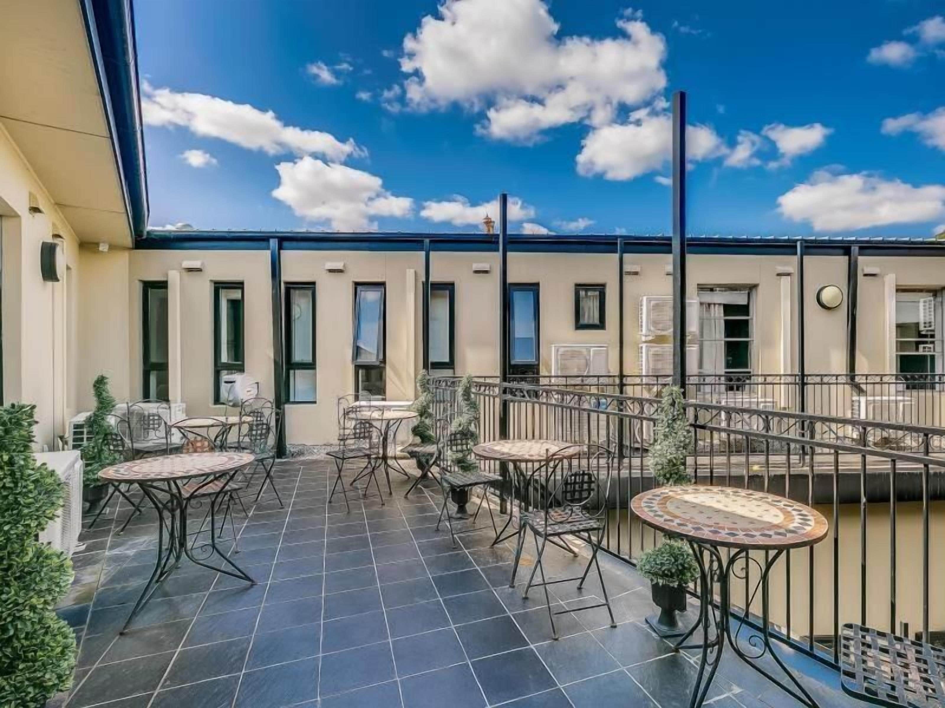 A rooftop terrace with outdoor seating and a view of the sky.