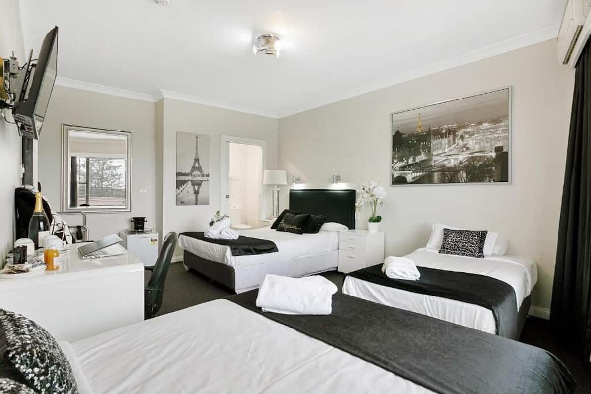 A hotel room with two beds, a desk, a chair, a TV, and a large window.