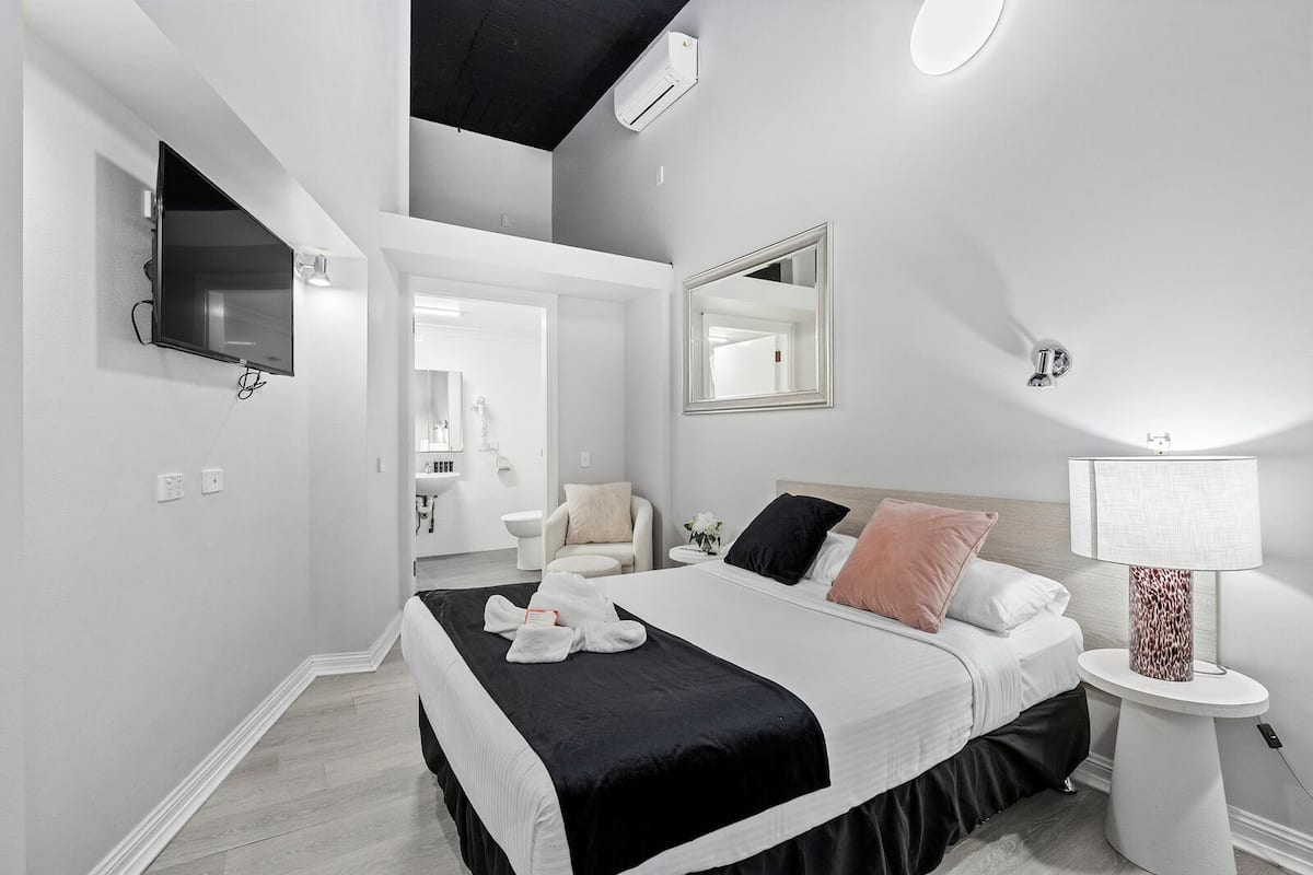 A modern bedroom with a bed, bedside table, and a TV mounted on the wall.