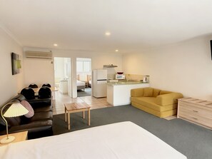 Ein kompaktes Hotelzimmer mit Bett, Schlafsofa, Esstisch, Küchenzeile und kleinem Badezimmer.