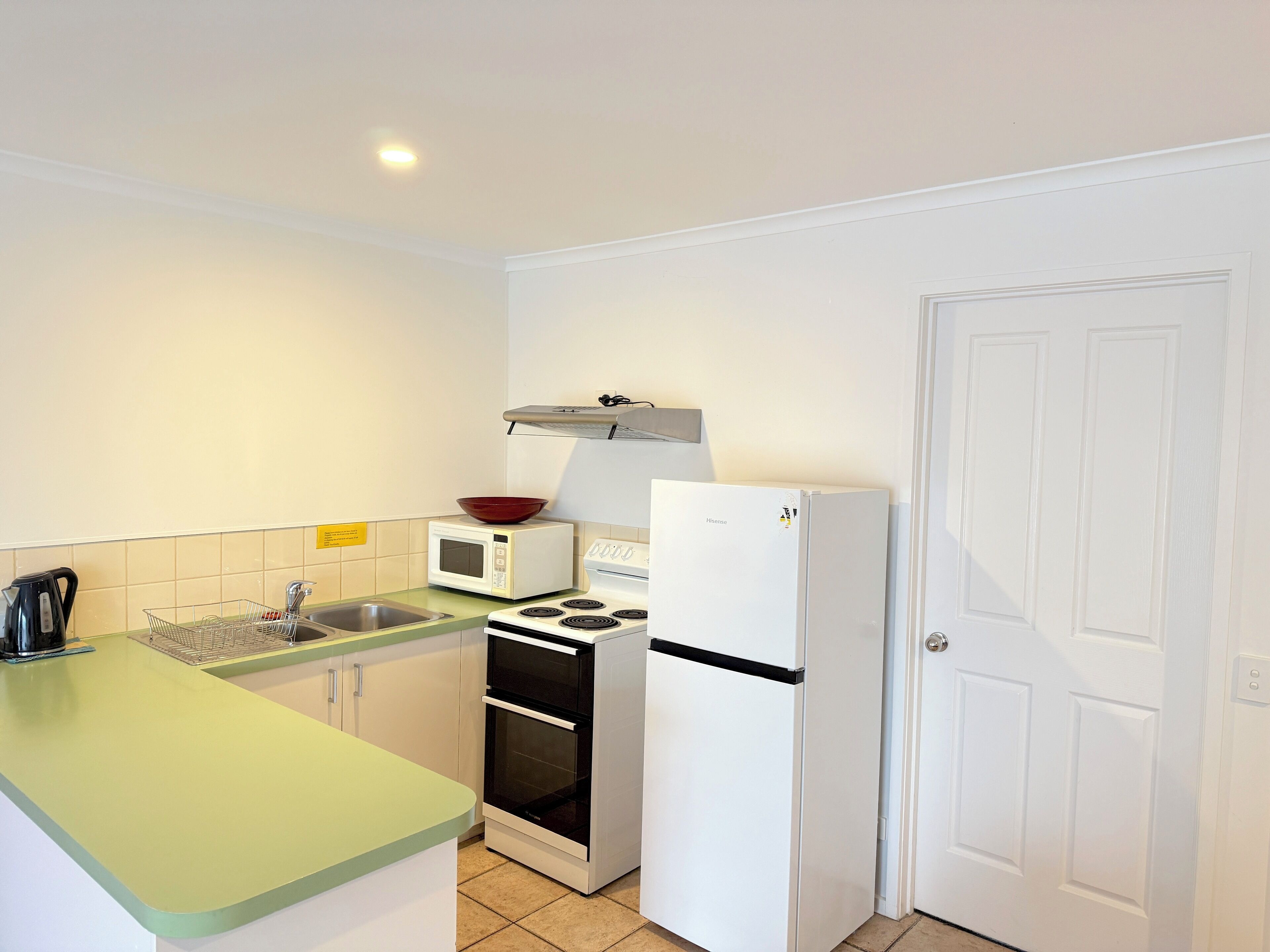 A compact kitchen with a sink, a microwave, a stove, and a refrigerator.