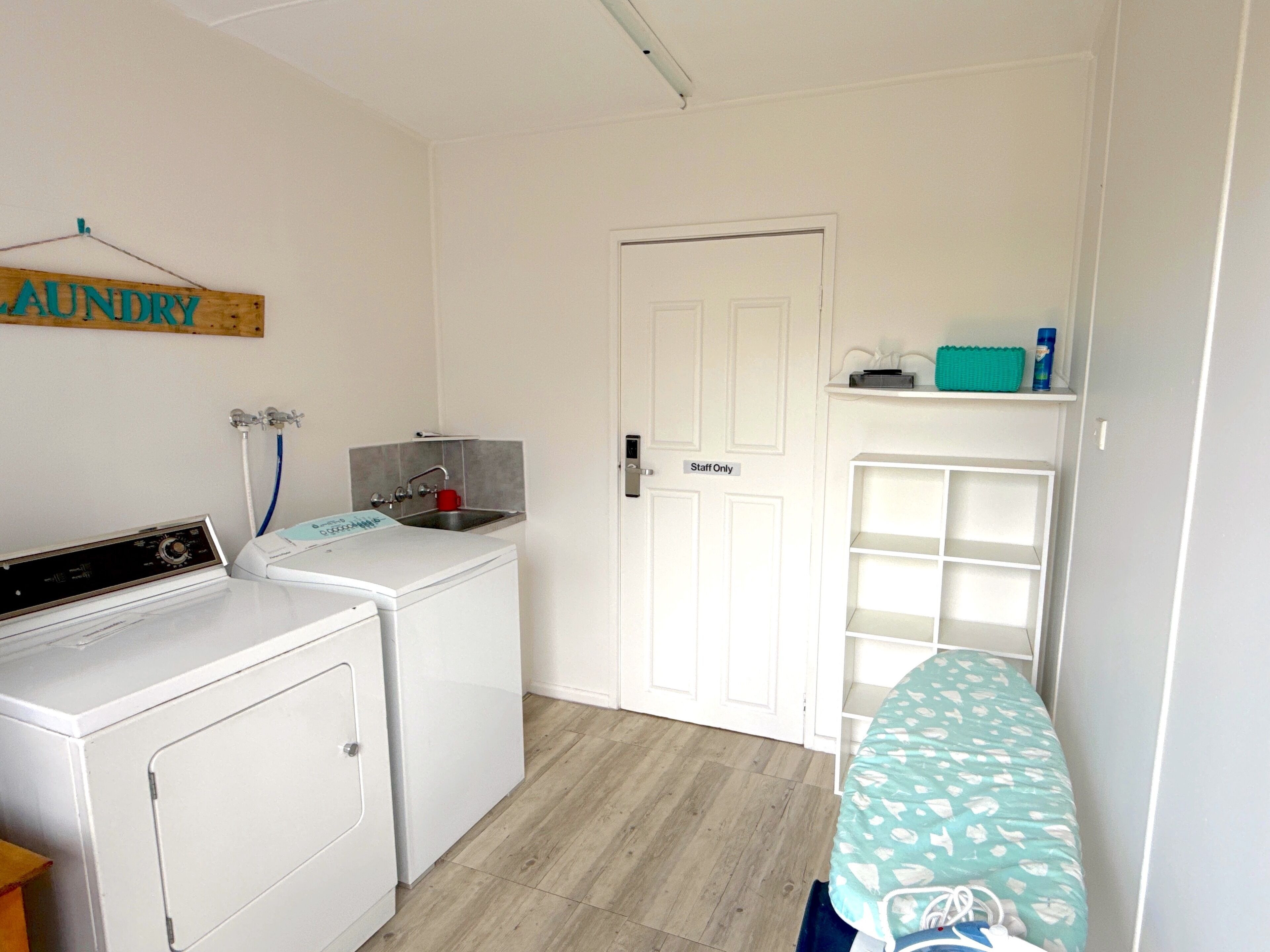A laundry room with a washing machine, a sink, and a 'Staff Only' door.