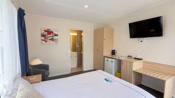 Une chambre d’hôtel comprenant un lit, un bureau, une télévision, une salle de bain et une kitchenette.