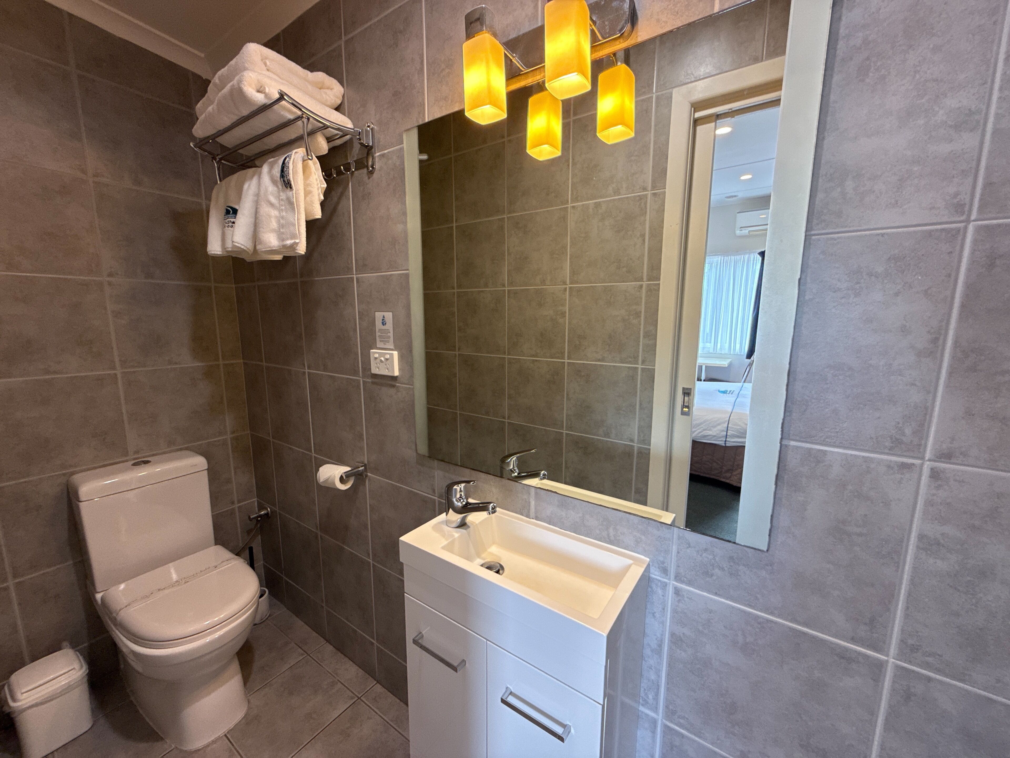 Et badeværelse med toilet, vask og håndklædeholder.