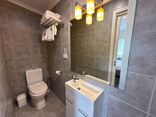 A modern bathroom with a toilet, sink, and towel rack.