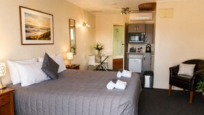 Habitación de hotel con una cama grande, un escritorio, una silla, un microondas y una pequeña kitchenette.
