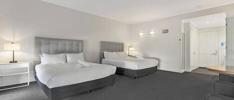A hotel room with two beds, a desk, and a chair.