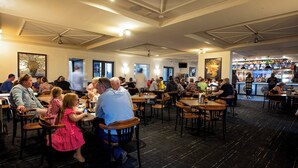 A spacious restaurant with multiple tables and chairs, a bar area, and a ceiling with a fan. - Caledonian Hotel Motel (Echuca)