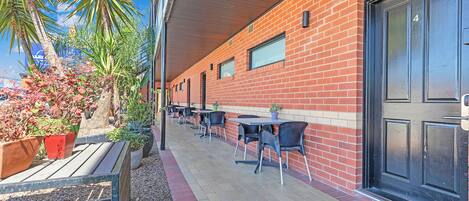 An outdoor patio with brick walls, black doors, and outdoor seating.