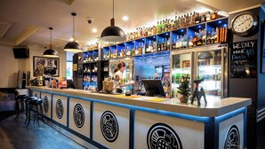 A bar with a counter, shelves of liquor bottles, and a clock on the wall. - Caledonian Hotel Motel (Echuca)