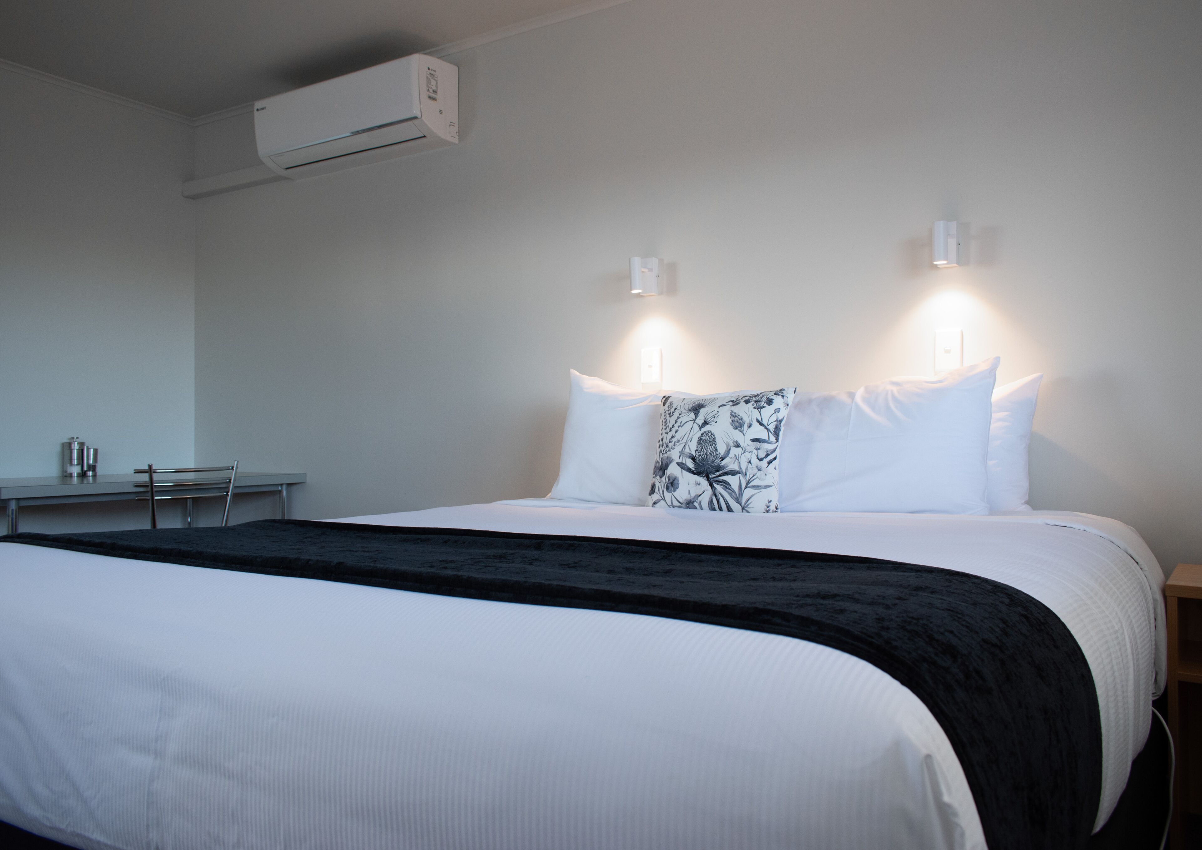 Une chambre d’hôtel équipée d’un lit, de tables de chevet, d’un appareil de climatisation et d’un système d’éclairage mural.