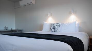 Une chambre d’hôtel équipée d’un lit, de tables de chevet, d’un appareil de climatisation et d’un système d’éclairage mural.