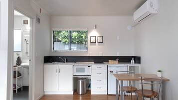 Una cocina moderna con armarios blancos, un microondas, un fregadero y una ventana con persianas.