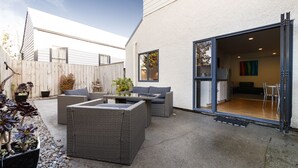 A patio area with wicker furniture, a glass door leading to an interior space, and potted plants. - Drovers Motor Inn (Palmerston North)