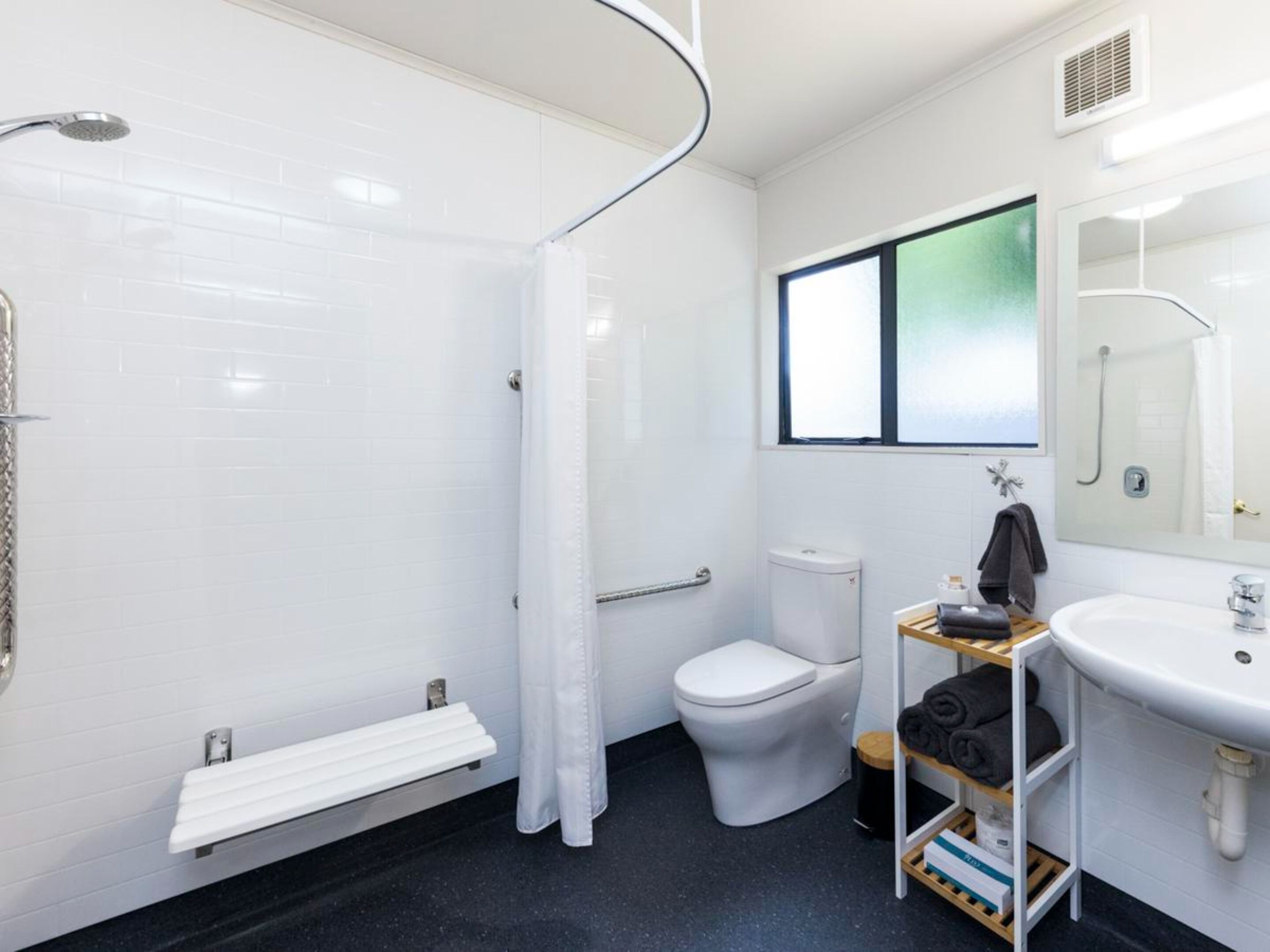 A modern bathroom with a shower, toilet, and sink.