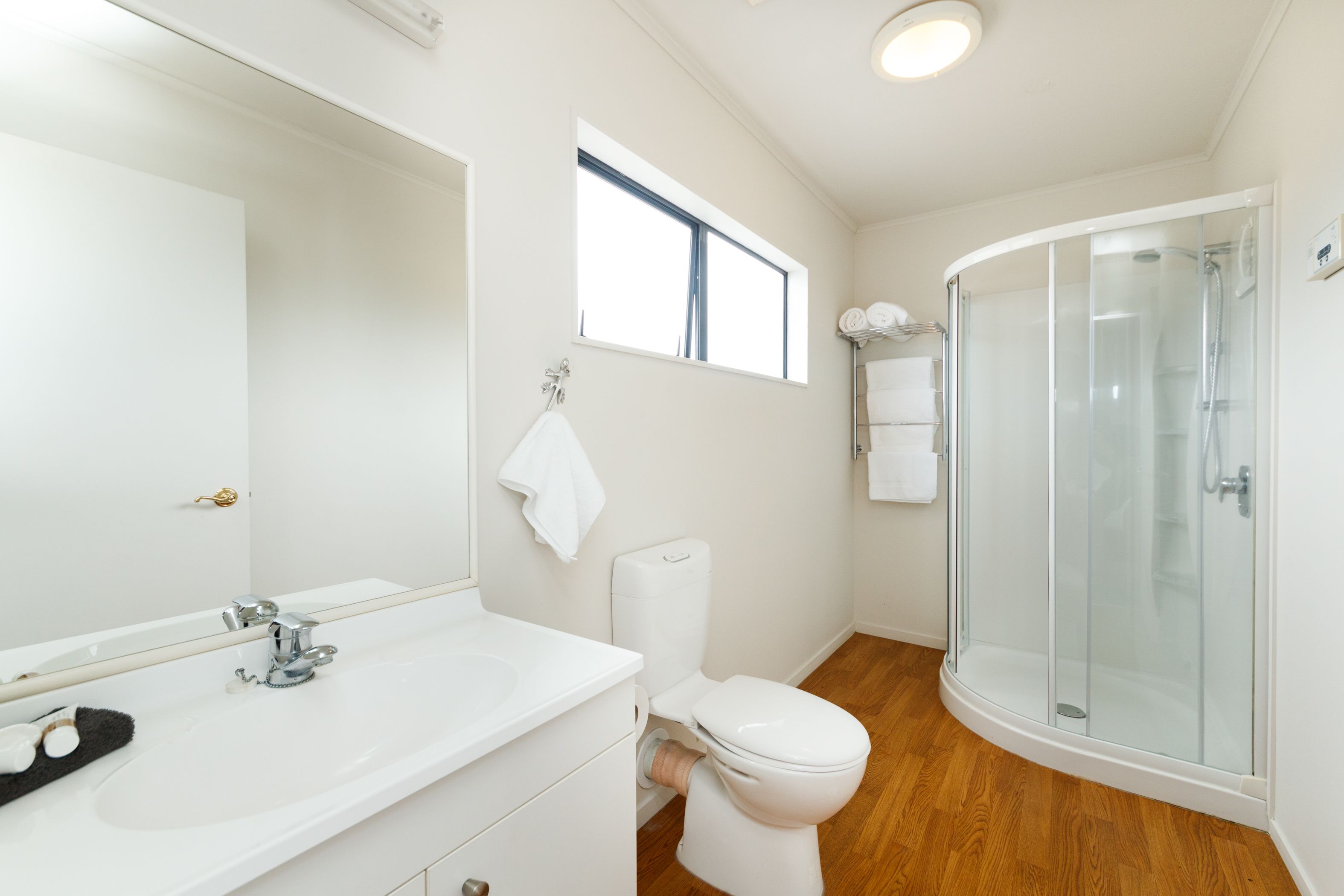 A modern bathroom with a white sink, toilet, and glass shower enclosure.