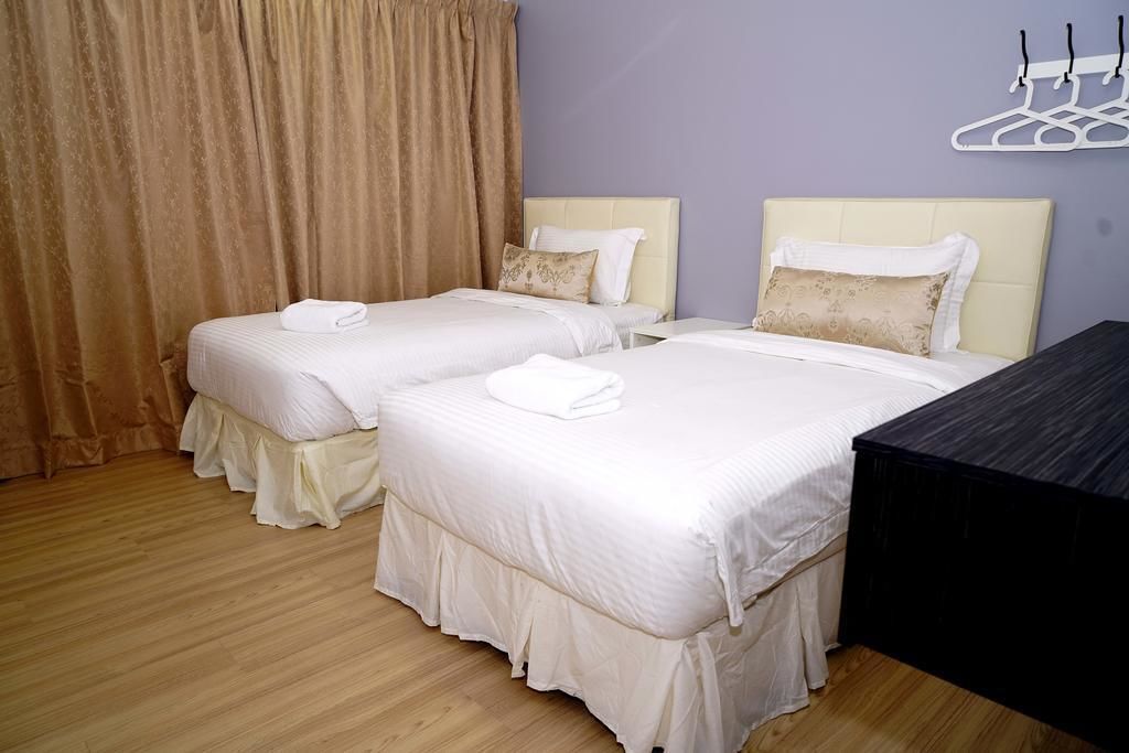 A hotel room with two beds, each with a white bedspread and a matching pillow. There is a wooden floor and a dark-colored dresser.