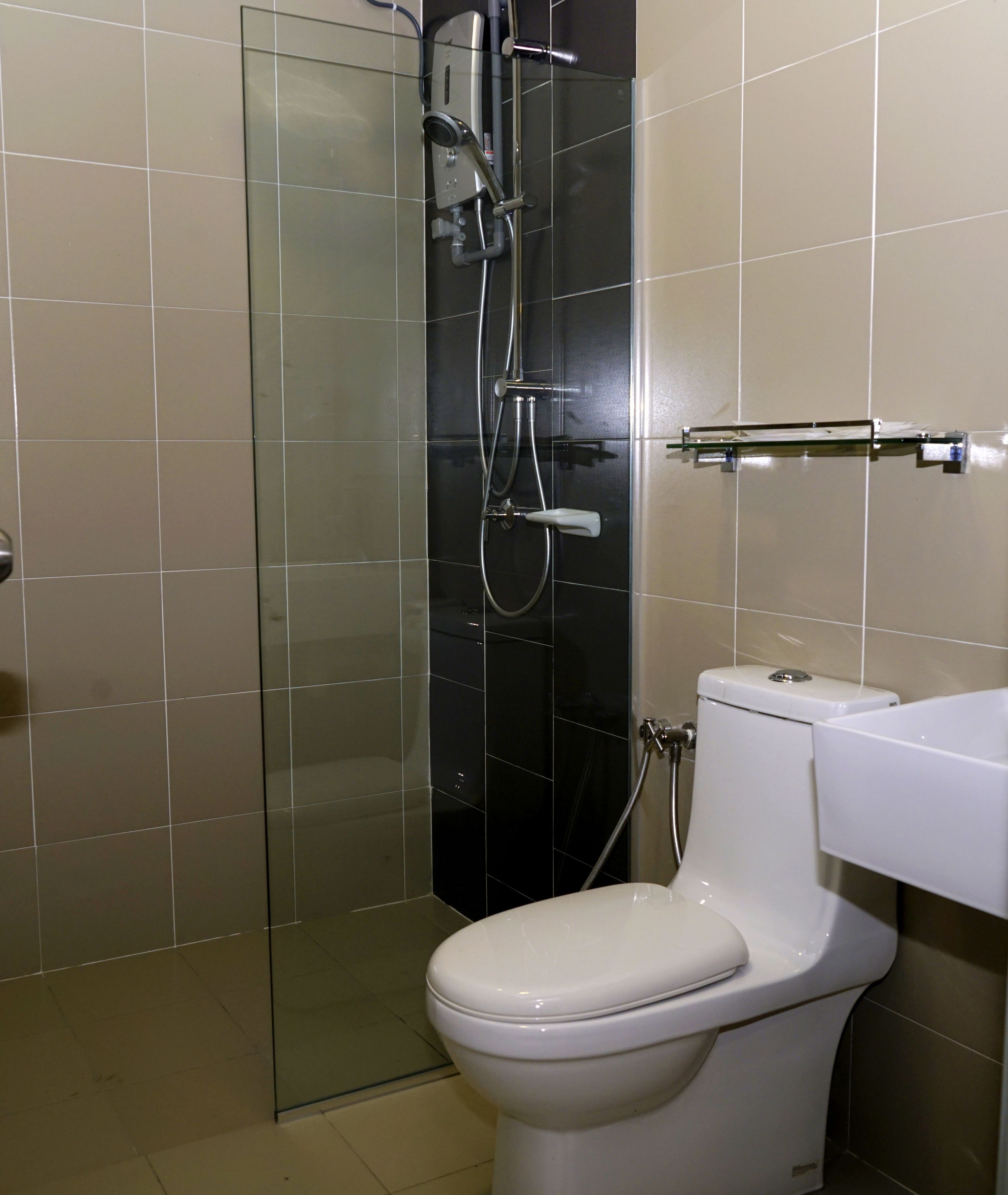 Un baño con ducha envuelta en vidrio, inodoro blanco y lavamanos con espejo.