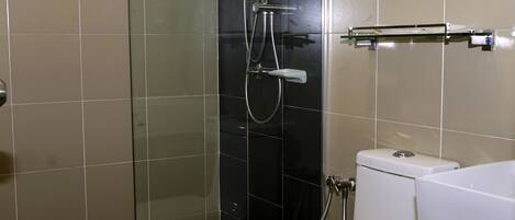 Un baño con ducha envuelta en vidrio, inodoro blanco y lavamanos con espejo.