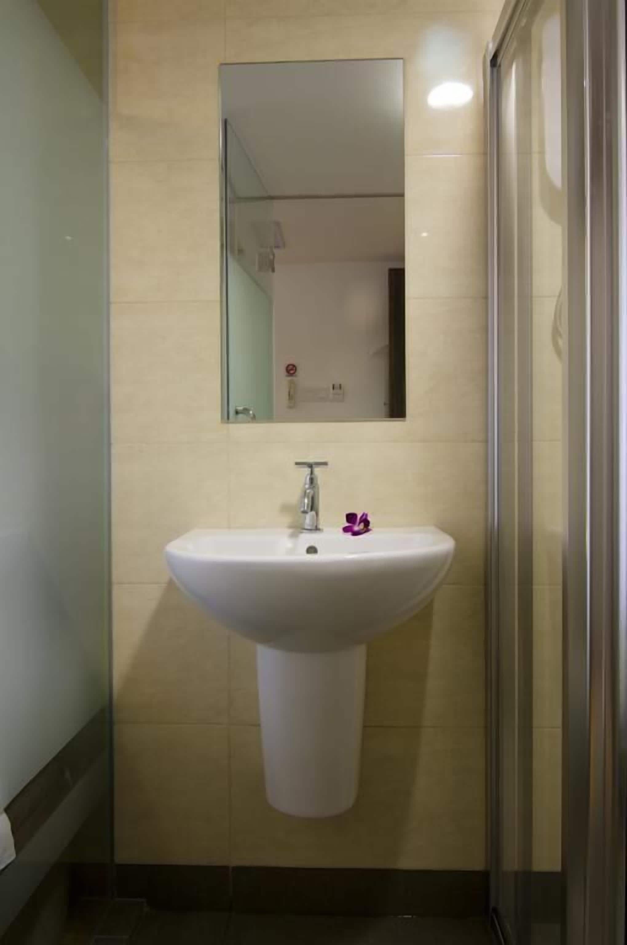 Un baño con un lavamanos pedestal blanco, un espejo encima y una cabina de ducha de vidrio.