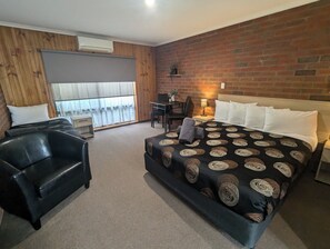 A hotel room with a large bed, a desk, a chair, and a view through a window. - Kyabram Country Motel (Kyabram)