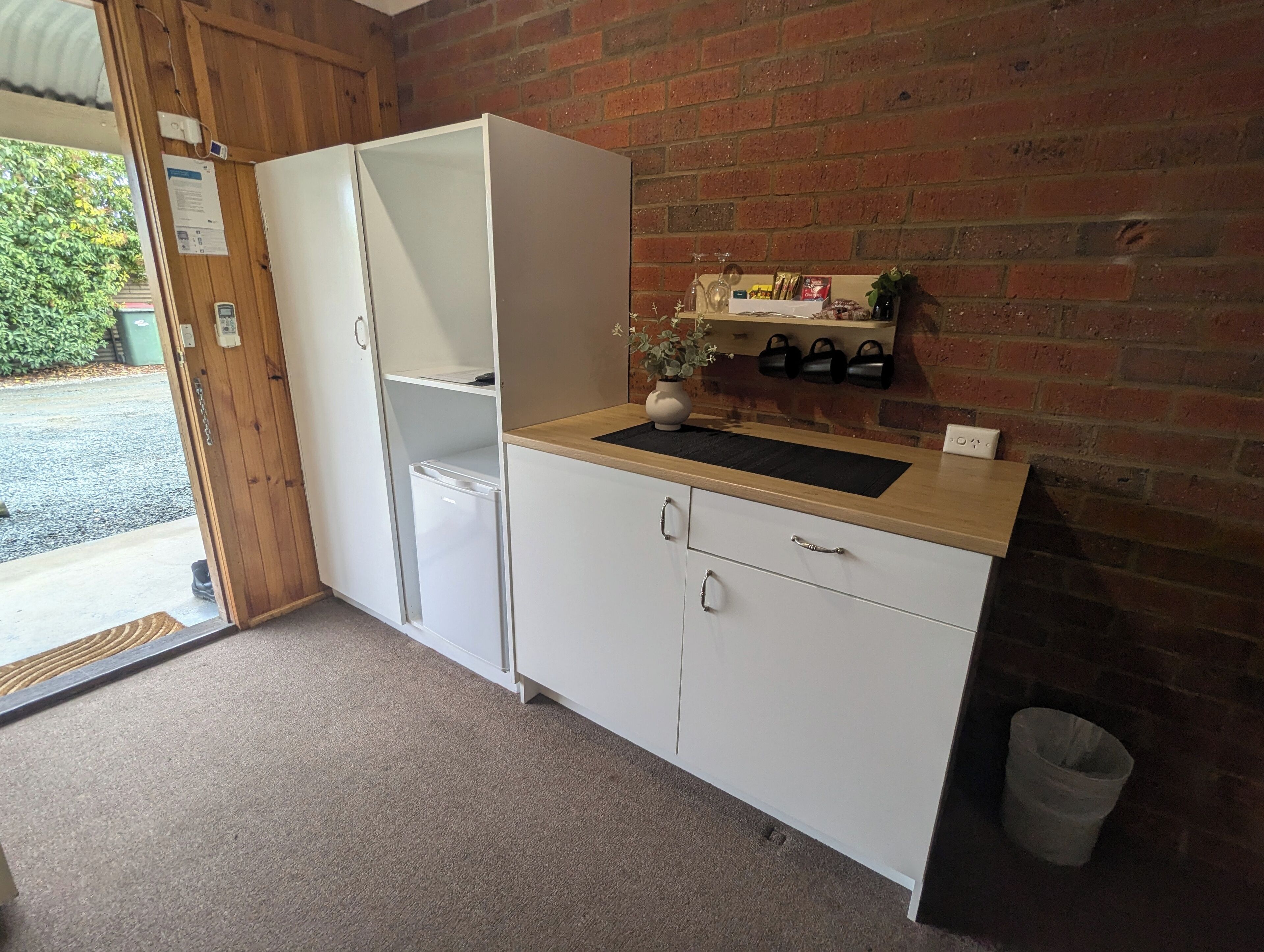 Una kitchenette compacta con refrigerador, pileta y una mesada pequeña.