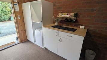 Una kitchenette compacta con refrigerador, pileta y una mesada pequeña.