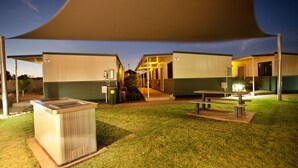 A building with a covered outdoor area, a trash bin, and a picnic table. - Karratha Lodge (Karratha Industrial Estate)