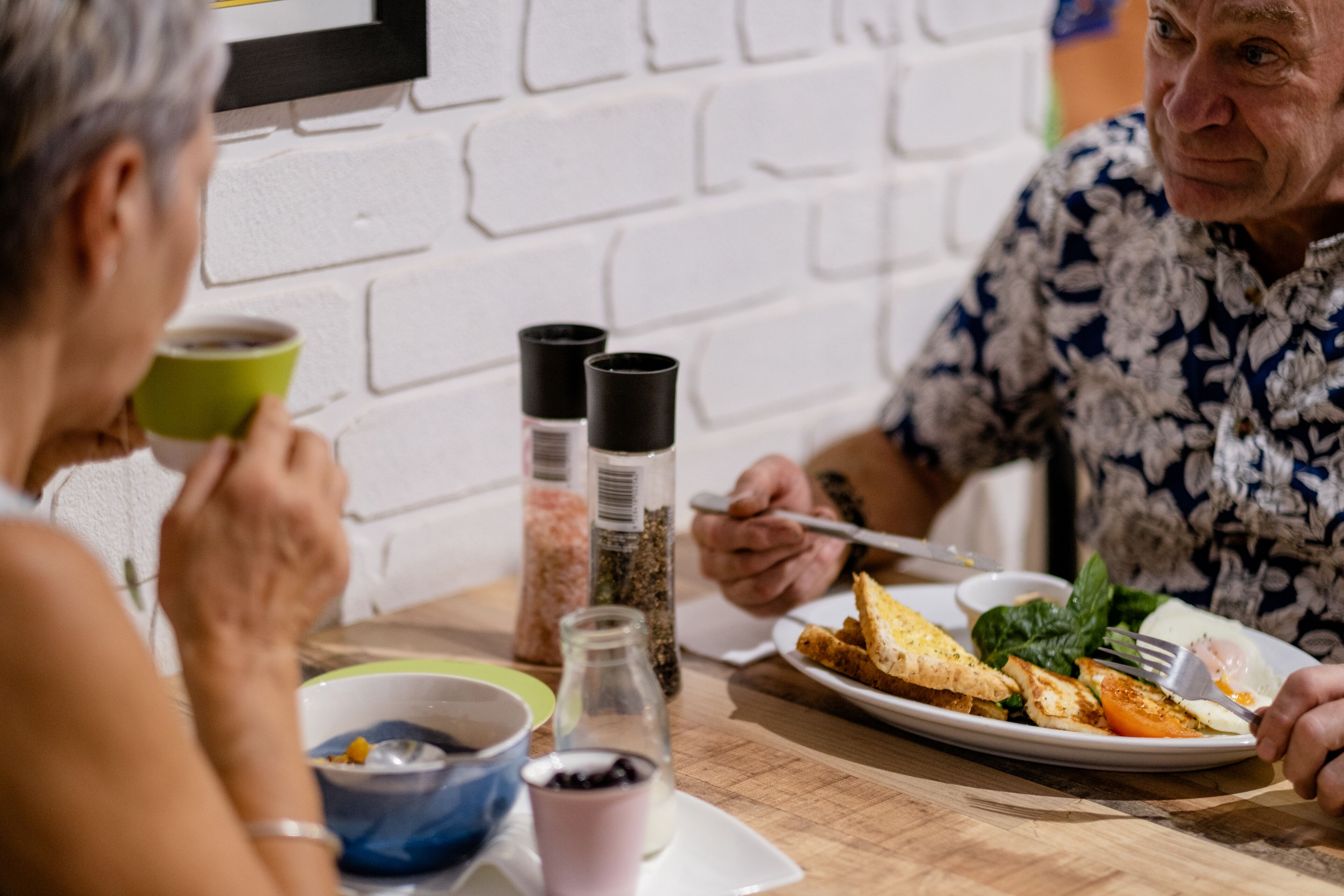 A dining table with a plate of food, a green cup, and condiments.