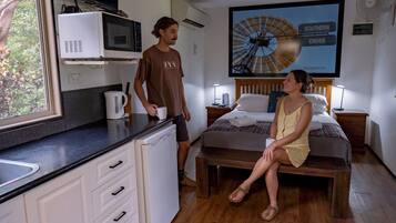 Una habitación moderna con cama, mesa de comedor y área de cocina que incluye microondas y cafetera.