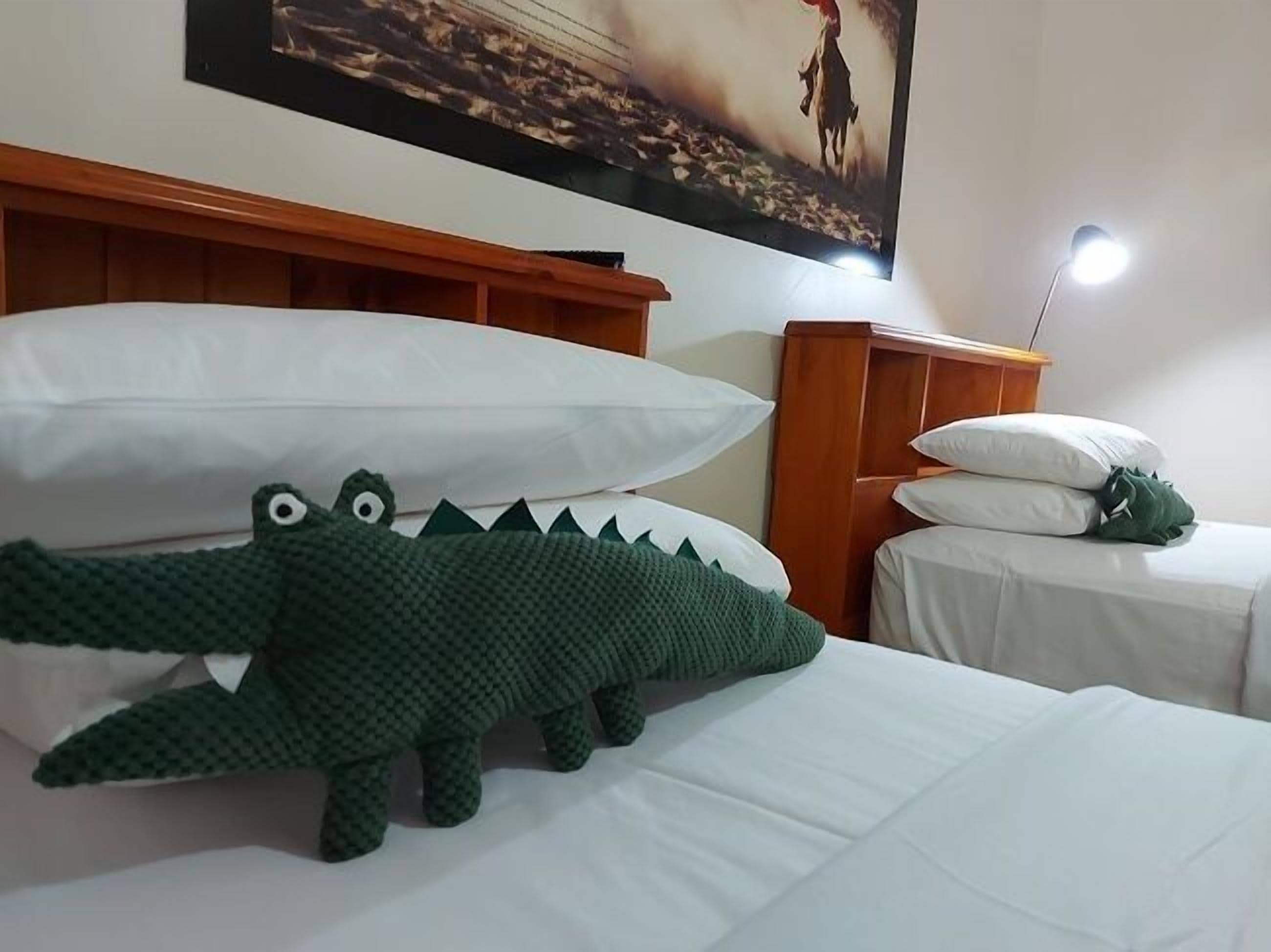 A hotel room with a bed, a nightstand, a lamp, and a painting on the wall.