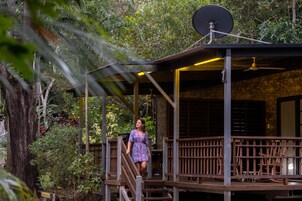 A woman walking on a wooden deck with a satellite dish and a ceiling fan.