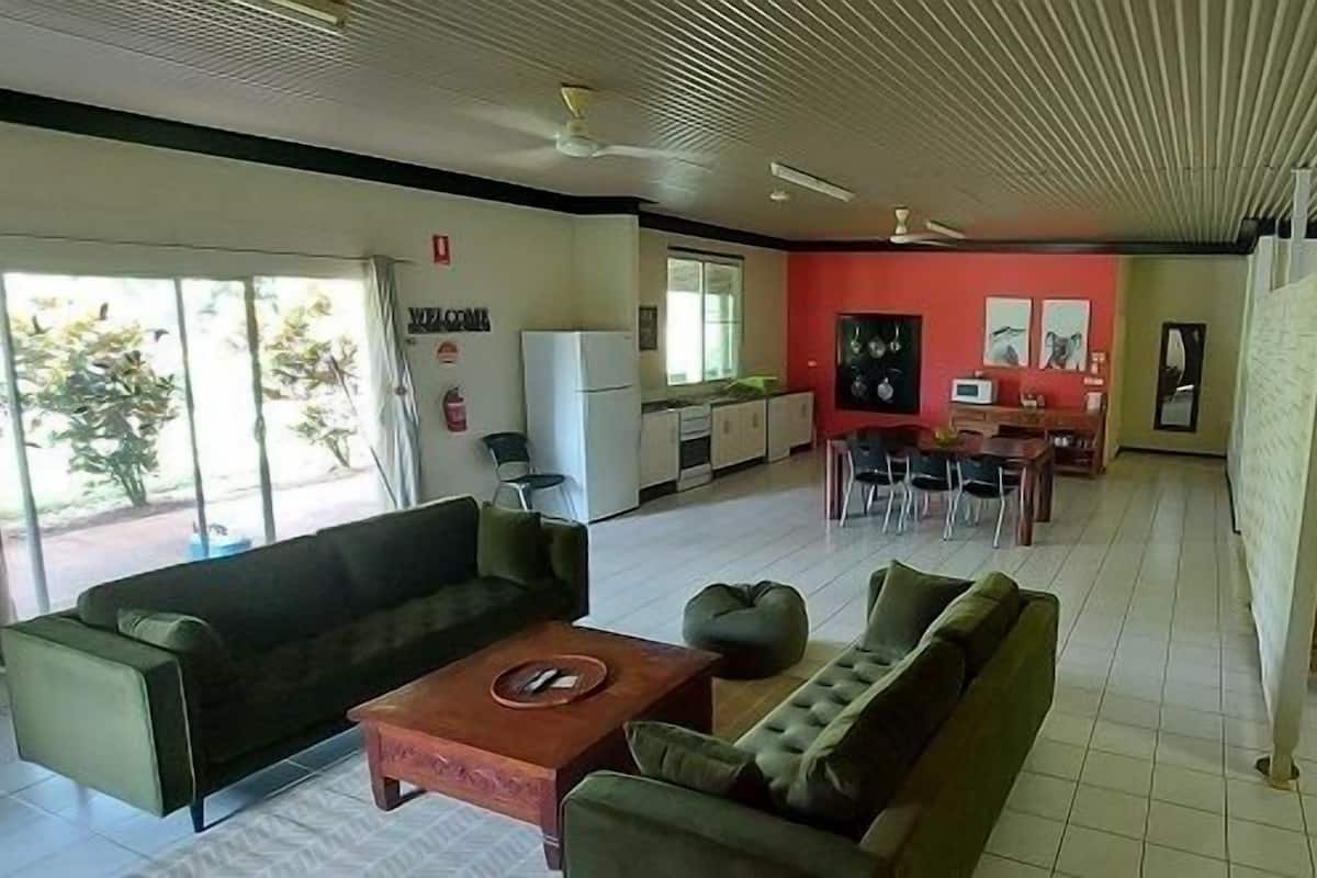 A spacious living area with a sofa, coffee table, and a dining area with chairs and a table.
