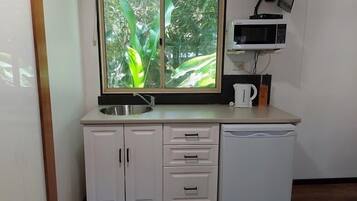 A compact kitchen with a window, a sink, a microwave, and a dishwasher.