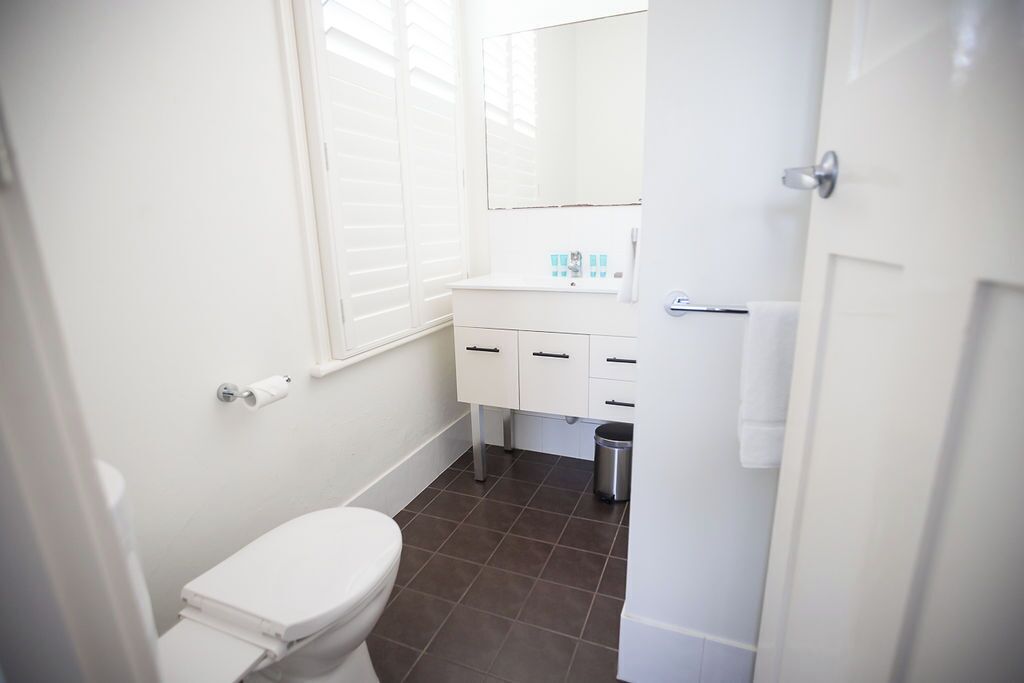 A small, white bathroom with a toilet, a sink, and a mirror.