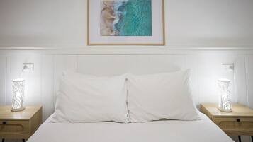 A hotel room with a bed, two bedside tables, a framed picture on the wall, and two wall-mounted lamps.