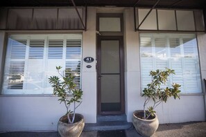 A building with a number 41 sign, a door, and two potted plants. - Albany Central Apartments (Albany)
