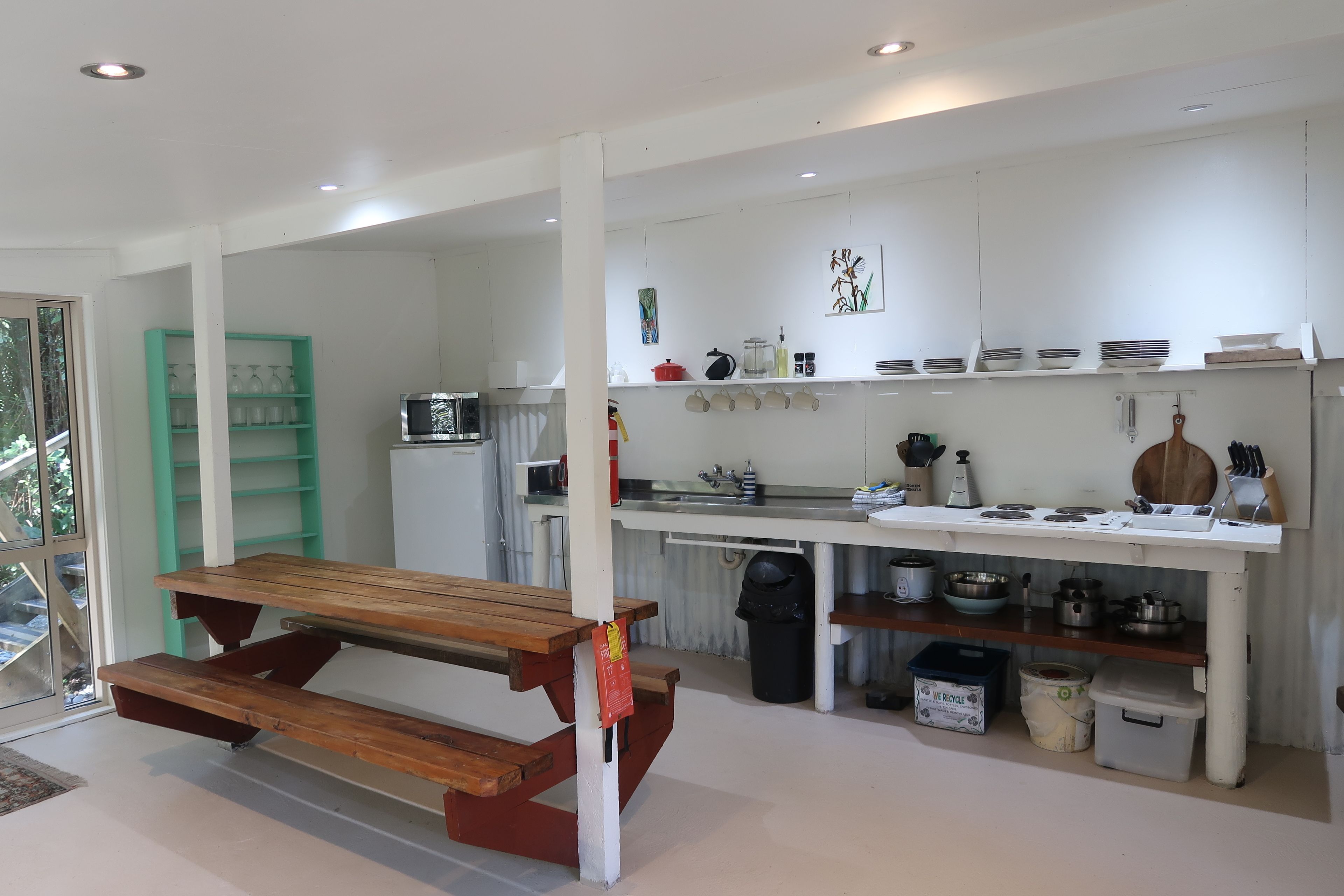 A modern kitchen with a wooden table and benches, white cabinets, and various kitchen appliances.