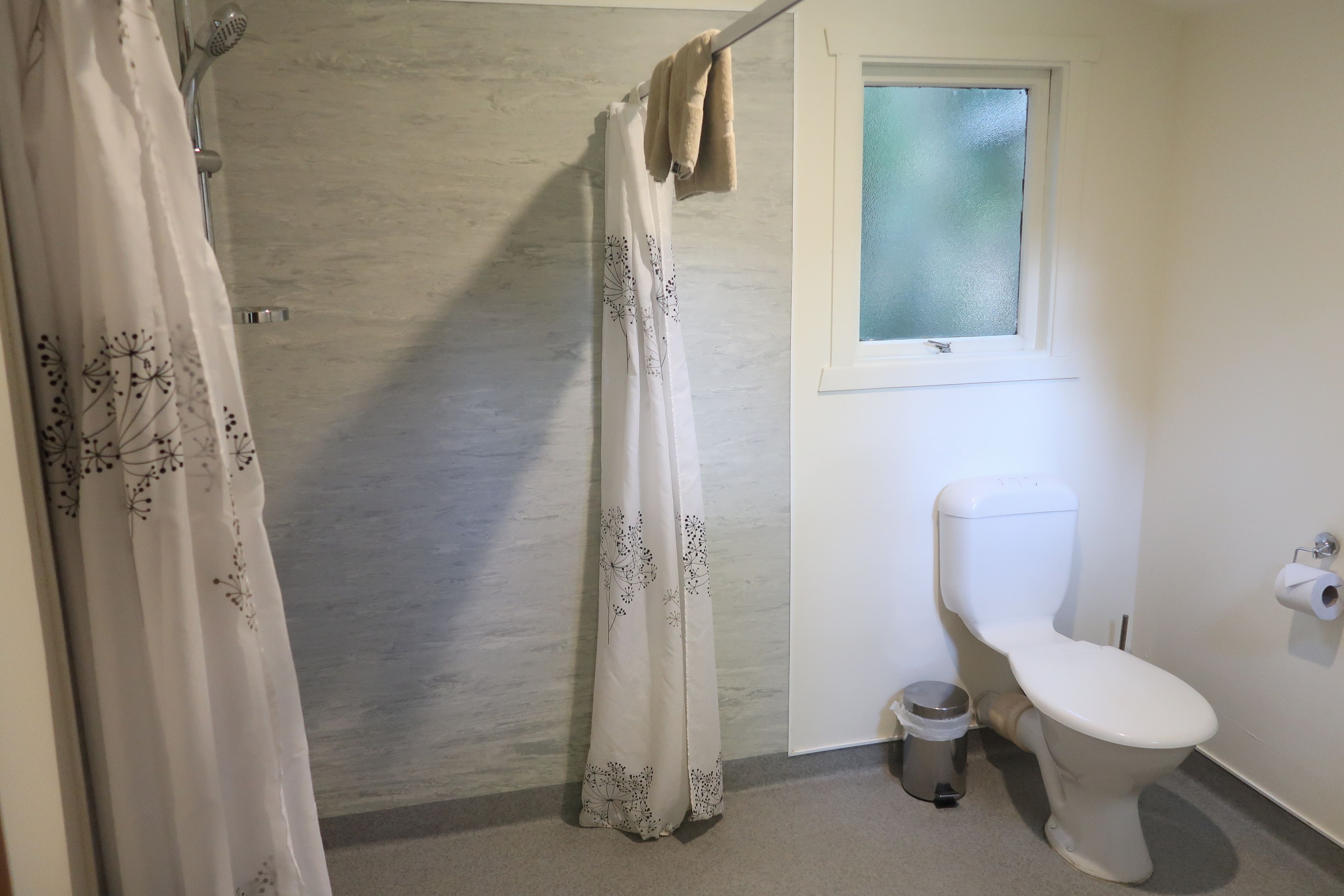 Un baño con cortina de ducha, inodoro y ventana.