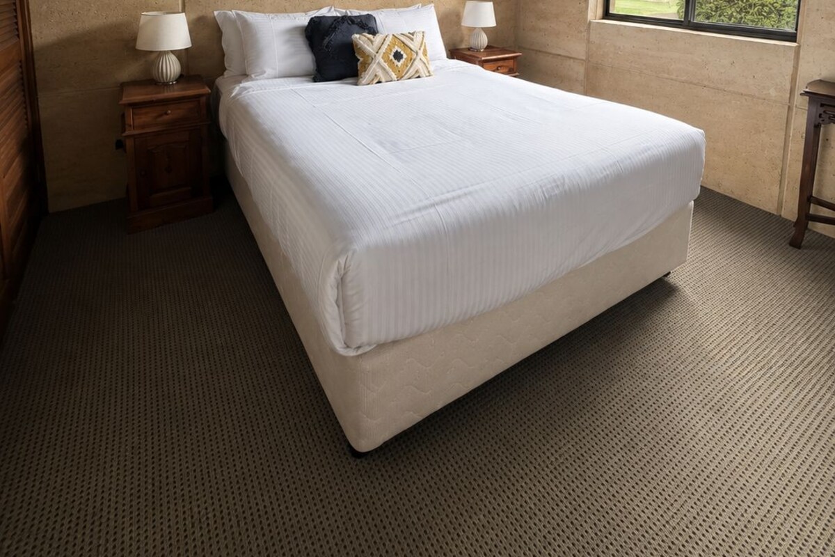 A bedroom with a large bed, wooden ceiling, a ceiling fan, a window with a view, and two bedside tables with lamps.