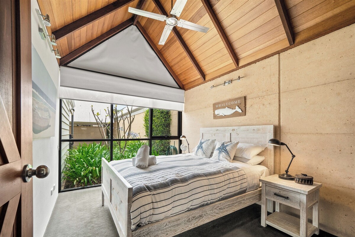 A bedroom with a bed, bedside table, lamp, and a ceiling fan.