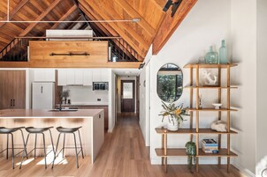 Una cocina moderna con techo de madera, una isla central con taburetes de bar y horno empotrado.