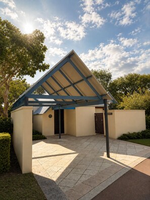 A modern building with a covered patio area, a flat roof, and a paved entrance. - Whalers Cove Villas (Dunsborough)
