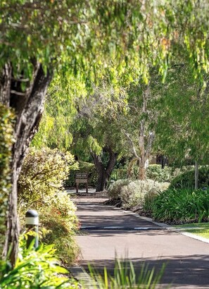 A pathway leading to a beach access sign, surrounded by lush greenery and trees. - Whalers Cove Villas (Dunsborough)
