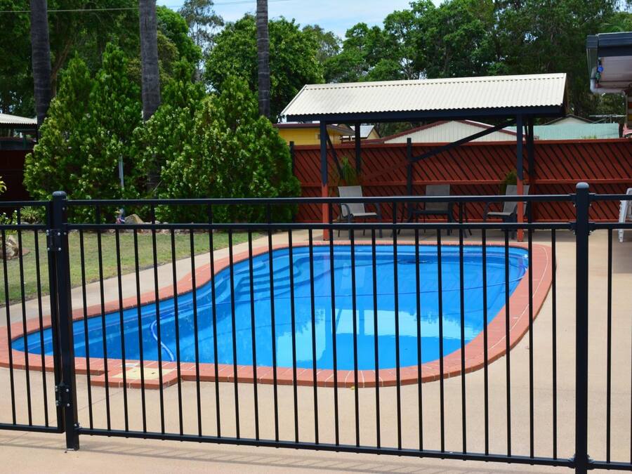 A rectangular swimming pool with a black metal fence surrounding it.