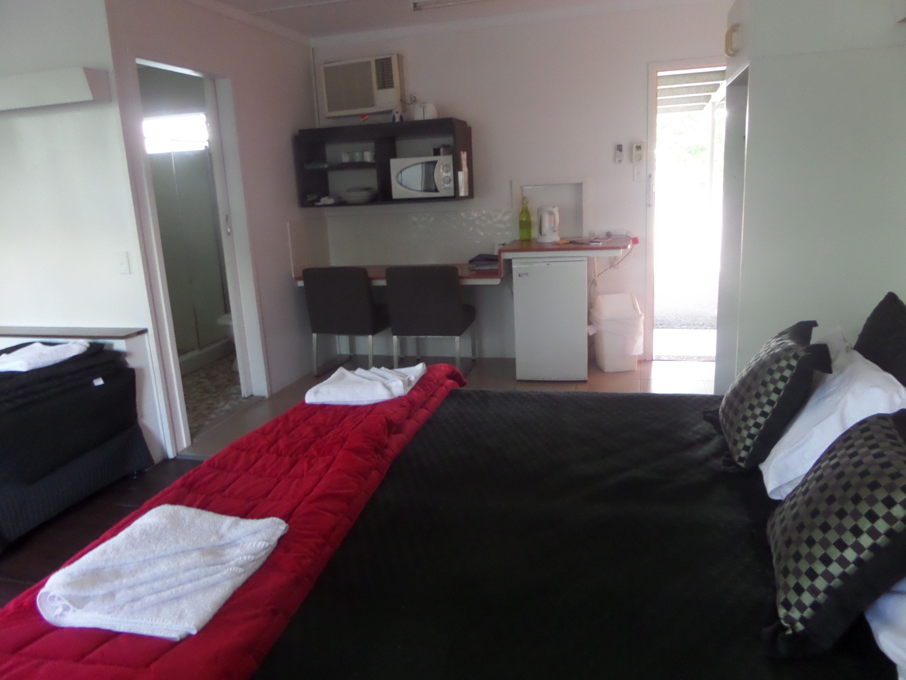 A hotel room with a bed, a desk, a microwave, and a small refrigerator.