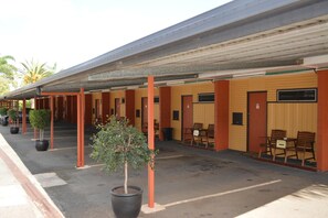 Un motel con varias habitaciones, un área de estar al aire libre techada y plantas en macetas.